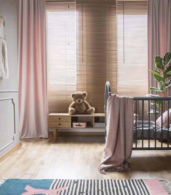 Drapes and blinds on windows in child’s bedroom interior with pi Drapes and blinds on windows in child's bedroom interior with pink blanket on bed. Real photo